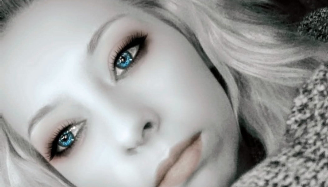 Close-up portrait of a woman with blonde hair, dark eyeliner, and striking, bright blue eyes.