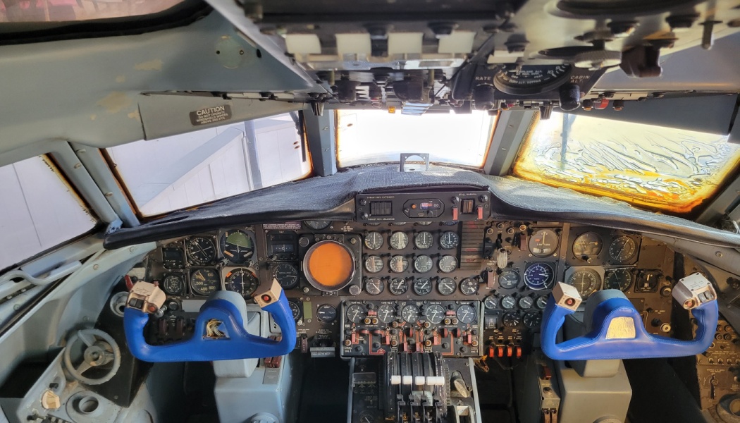 Vintage airplane cockpit with blue dual control yokes and an instrument panel packed with analog gauges and dials.