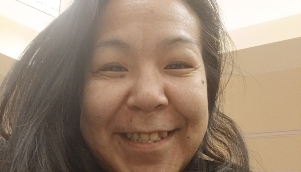 Close-up portrait of a woman with long dark hair smiling warmly at the camera.