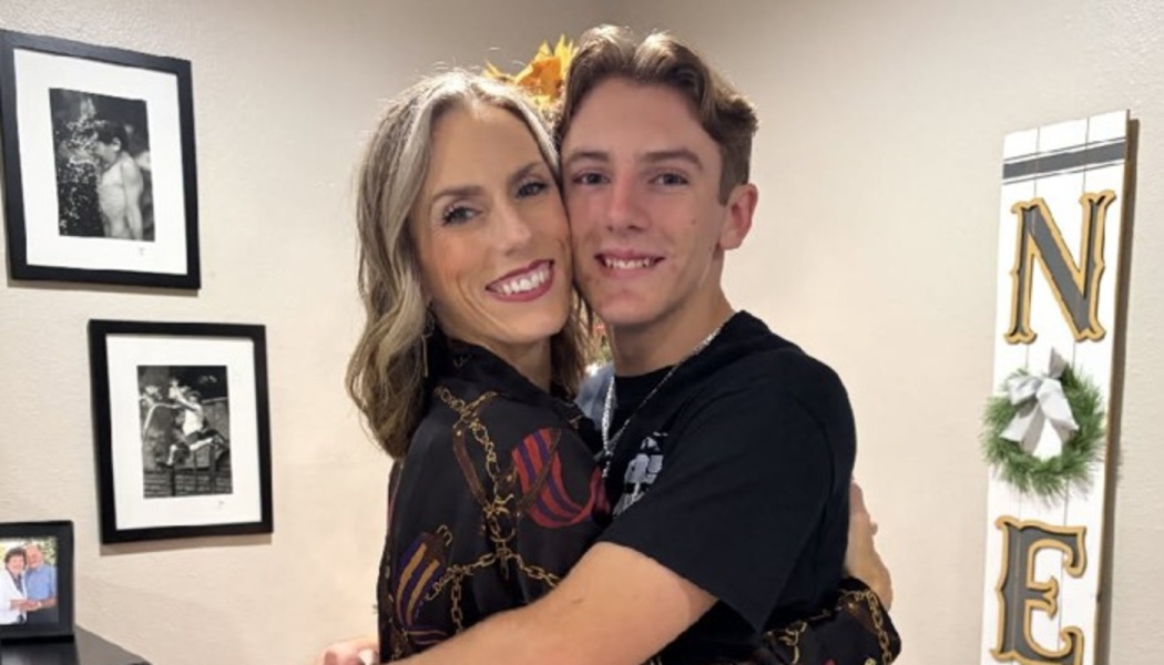 A smiling woman and a teenage boy embrace warmly, posing together cheek-to-cheek.
