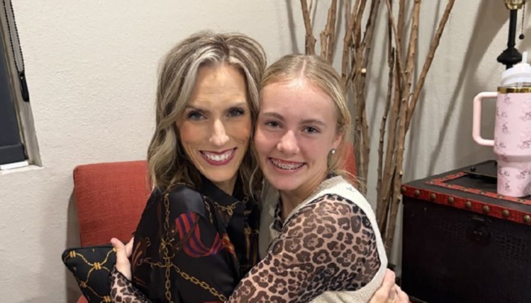 A smiling woman and a teenage girl with braces hugging cheek-to-cheek.