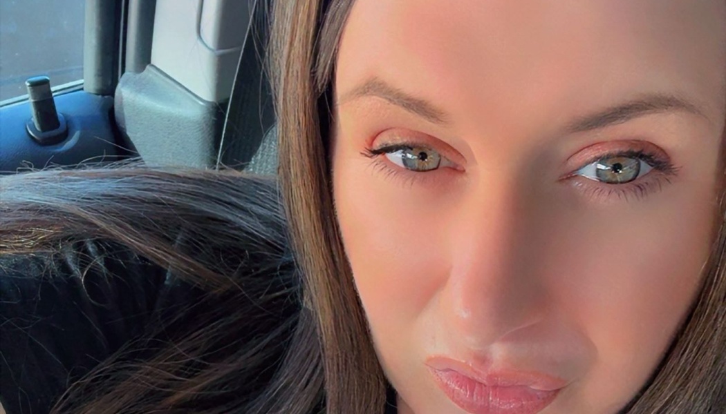 Close-up portrait of a woman with long dark hair and hazel eyes looking at the camera.