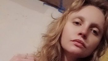 Close-up portrait of a woman with blonde, wavy hair looking directly at the camera.