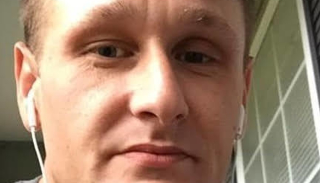Close-up selfie of a man wearing white wired earphones.