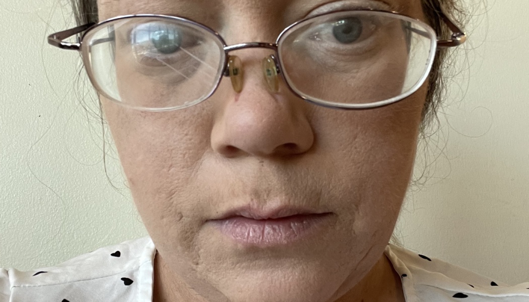 Close-up of a woman wearing wire-rimmed glasses with a cracked right lens.