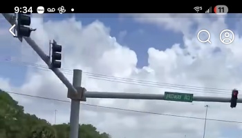 Traffic lights and a green Midway Rd street sign against a cloudy blue sky.