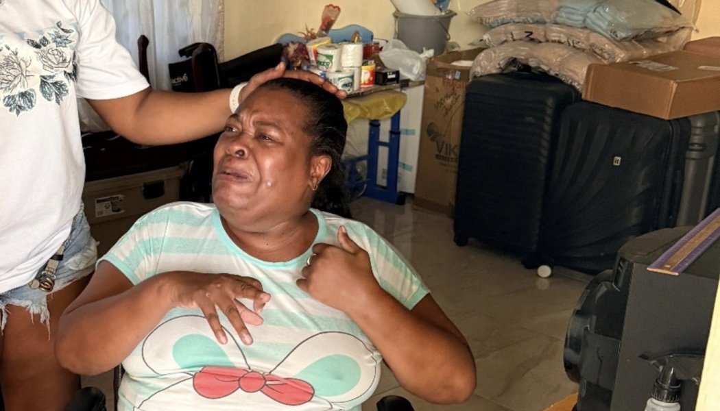A woman crying emotionally in a packed room receives a comforting hand on her head.