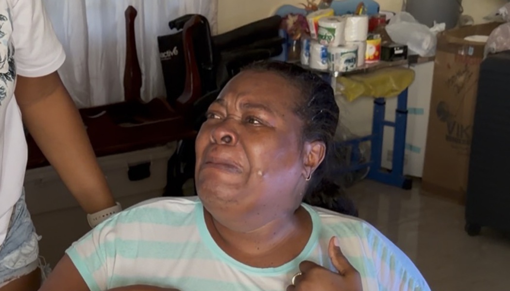 A tearful woman in a striped shirt crying with emotion, looking up while sitting indoors.