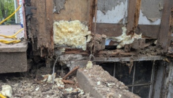 Severely rotted wooden house framing and crumbling foundation filled with expanding spray foam insulation.