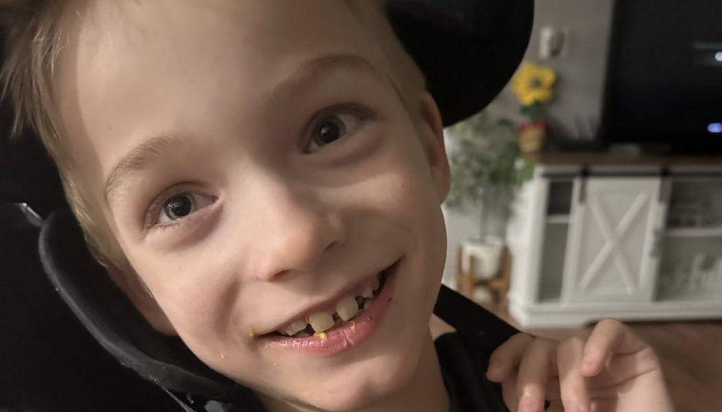 Close-up portrait of a happy young boy smiling brightly at the camera.