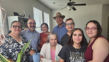 A loving multi-generational family smiling together around an elderly relative receiving oxygen at home.