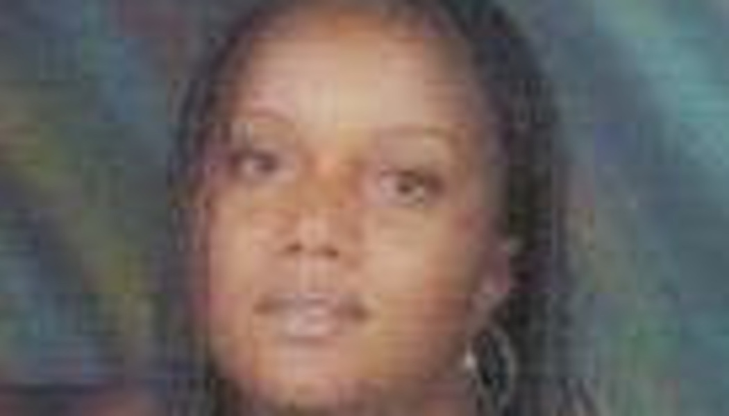 Close-up portrait of a Black woman with dark braided hair and hoop earrings against a teal backdrop.