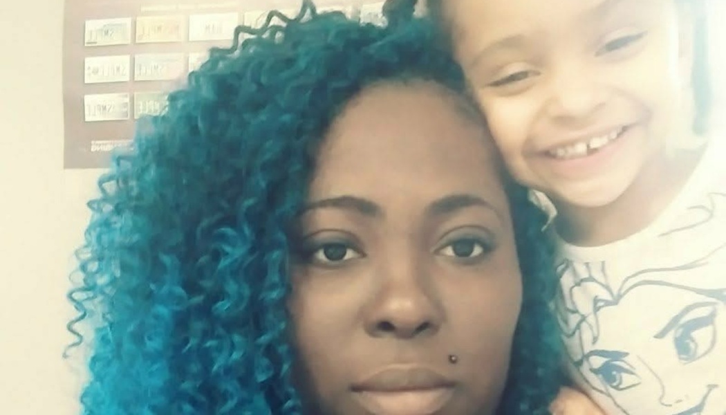 A woman with vibrant blue curly hair posing close to a smiling young child resting against her.