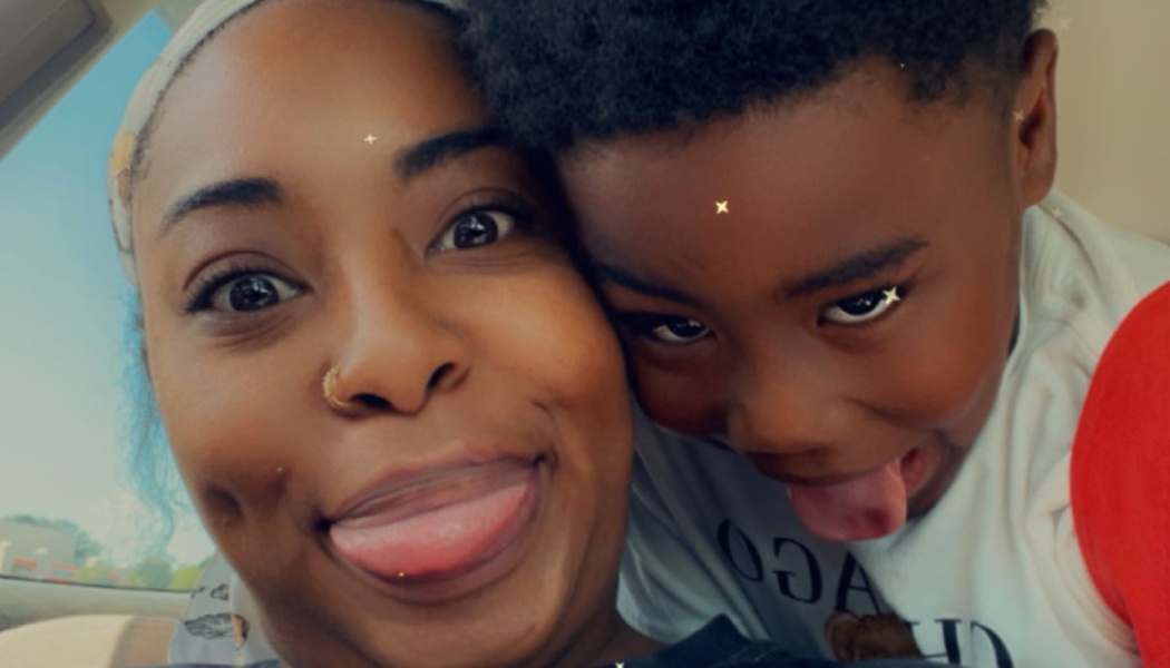 A Black woman and young boy in a car, playfully sticking their tongues out for a close-up selfie.