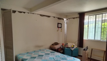 Bedroom with severe structural damage, featuring large cracks along the upper walls and corner.