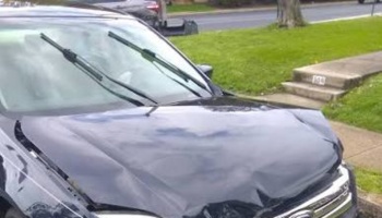 Black Ford car with severe front-end damage and a heavily crumpled hood after an accident.