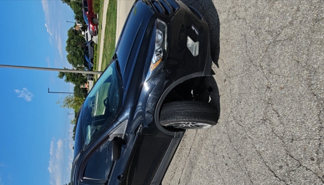 Black SUV with a broken front axle and severe damage, its front tire turned completely sideways under the wheel well.