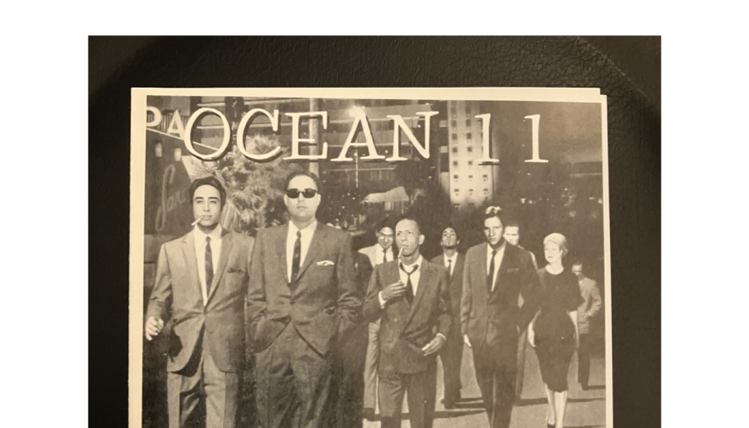 Black and white poster titled "OCEAN 11" featuring a group of people dressed in 1960s suits walking together.