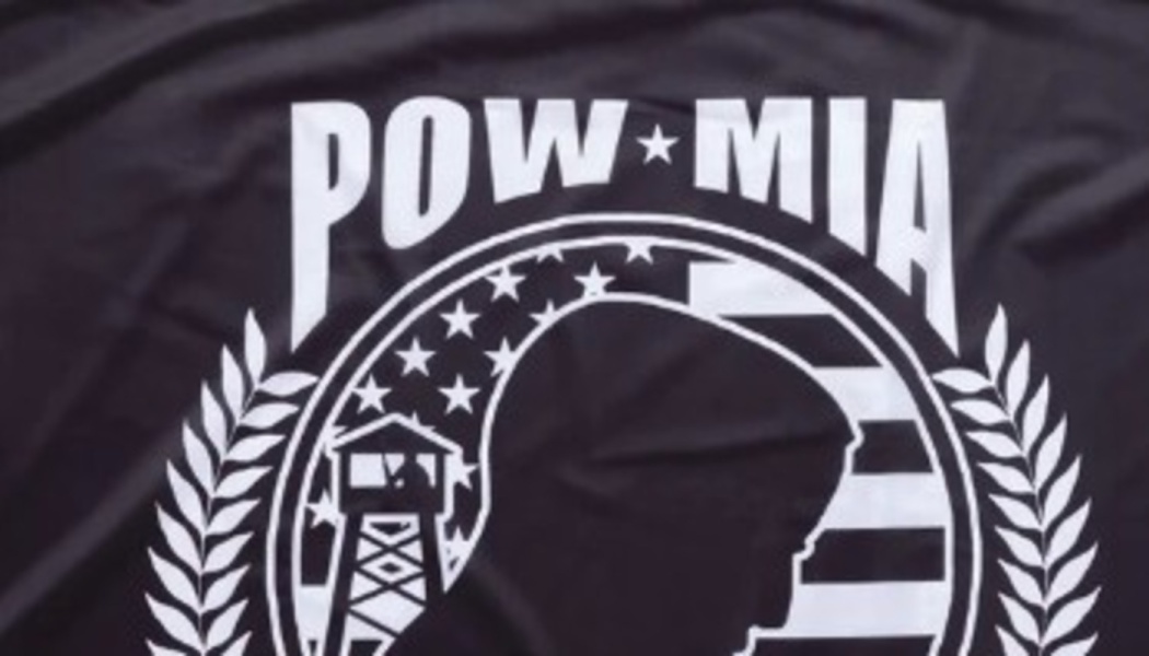 White POW MIA emblem on a black t-shirt, featuring a soldier's silhouette, guard tower, and American flag motif.