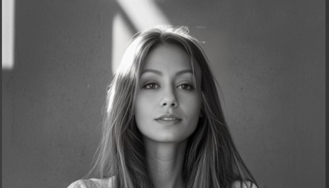 Black and white portrait of a young woman with long hair, looking directly at the camera with a subtle smile.