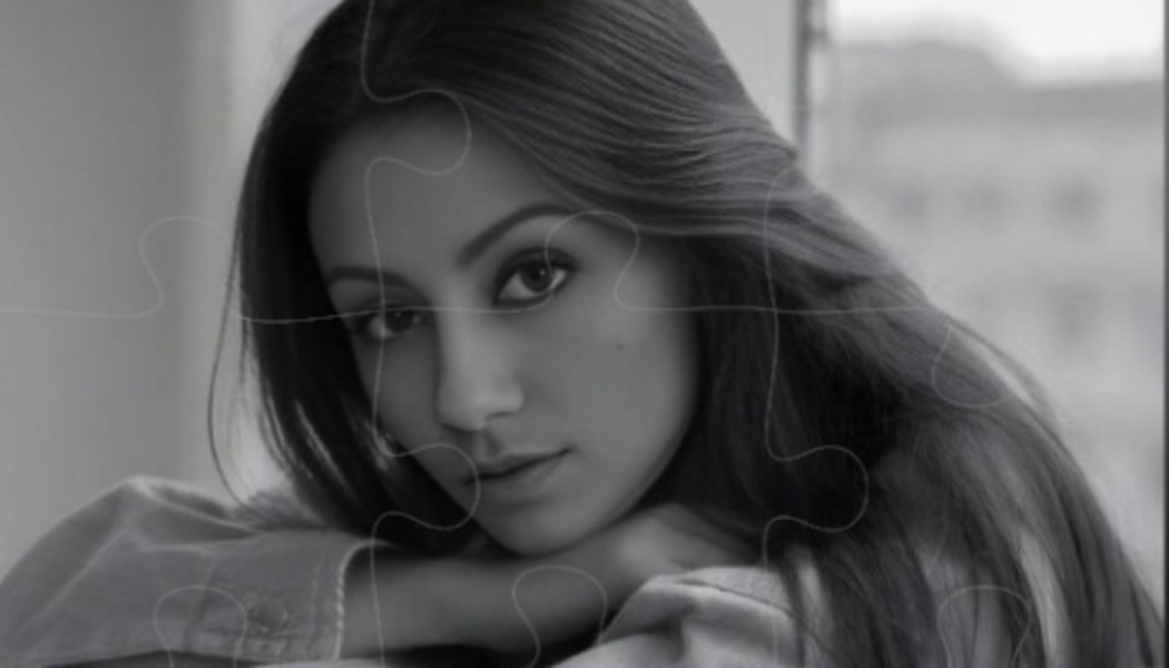 Black and white portrait of a young woman resting her head on her arms, overlaid with puzzle piece outlines.