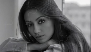 Black and white portrait of a young woman resting her head on her arms, overlaid with puzzle piece outlines.