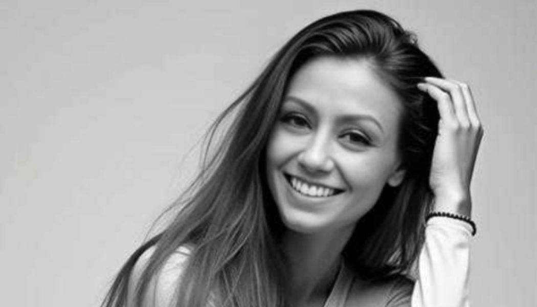 Black and white portrait of a smiling woman with long hair, running her hand through her hair.
