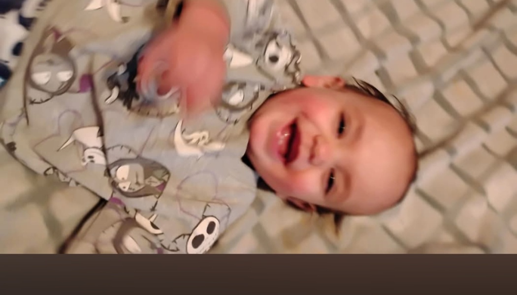 A smiling baby lying down while wearing Nightmare Before Christmas pajamas.