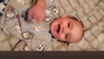 A smiling baby lying down while wearing Nightmare Before Christmas pajamas.