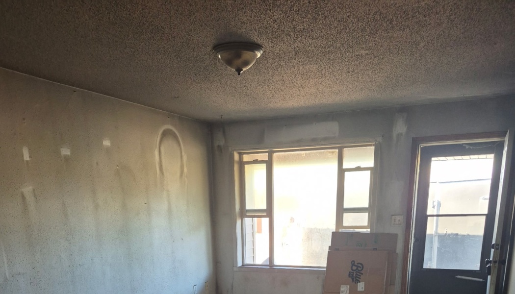 A room damaged by fire, showing heavy soot and smoke stains covering the walls and popcorn ceiling.