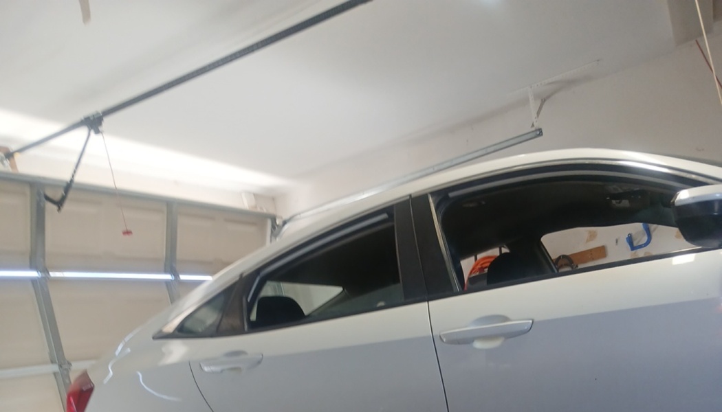 Side profile of a white sedan parked inside a residential garage.