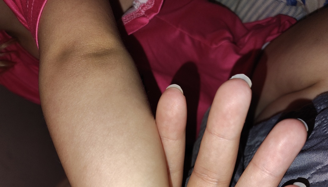 Close-up of a child's arm resting next to an adult's hand.