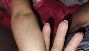 Close-up of a child's arm resting next to an adult's hand.