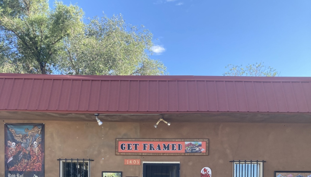 Exterior of an adobe building with a red roof and a sign reading "GET FRAMED" above the entrance.