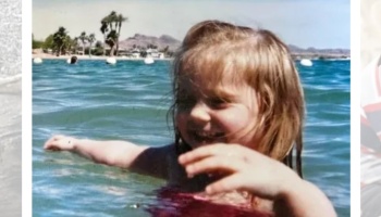 A smiling young girl playing in blue water with her arms outstretched and palm trees in the background.