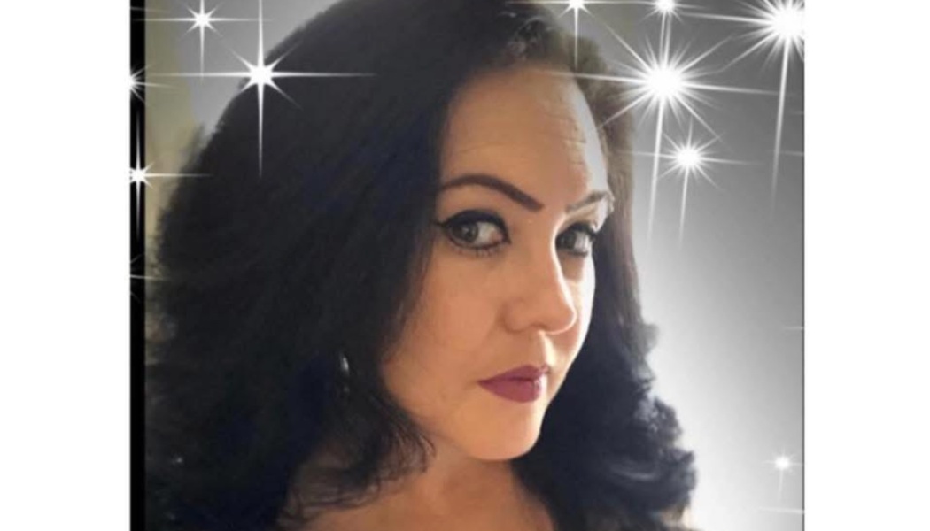 Close-up portrait of a woman with dark wavy hair and dark lipstick, surrounded by sparkling star overlays.