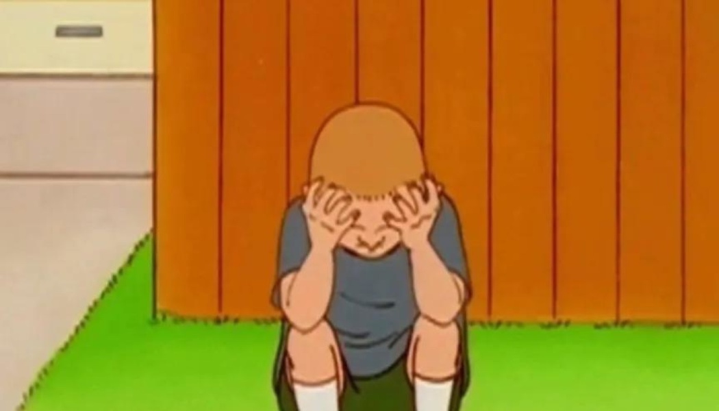 Animated boy crouching on grass with his head in his hands, looking distressed and overwhelmed.
