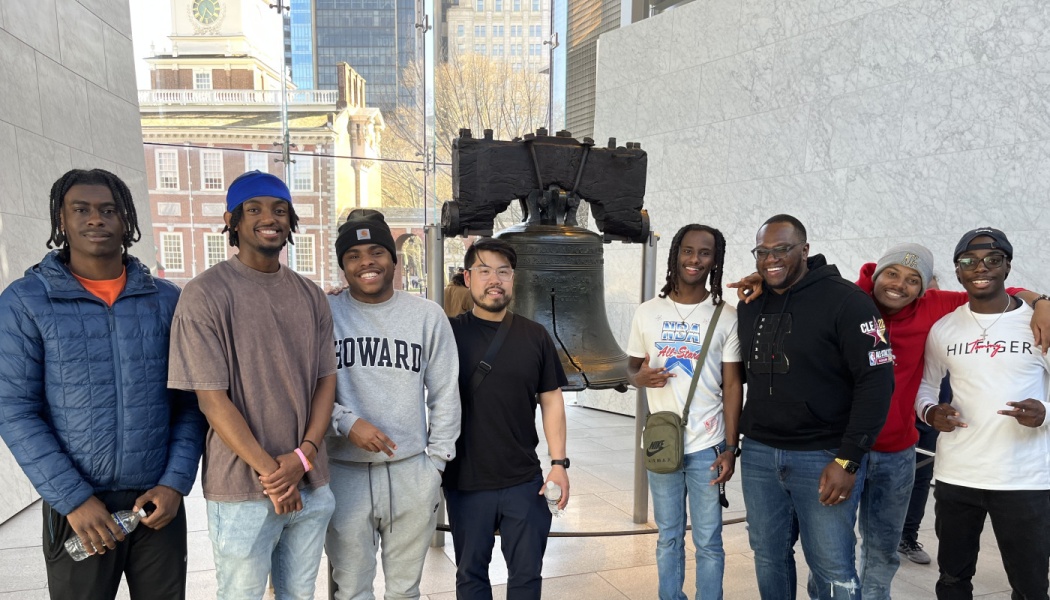 Group of young men posing together in front of the Liberty Bell in Philadelphia.