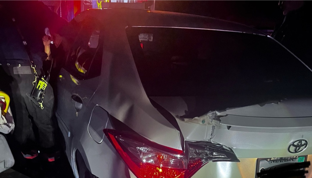 Silver Toyota sedan with severe rear-end damage to the trunk and taillight at night.