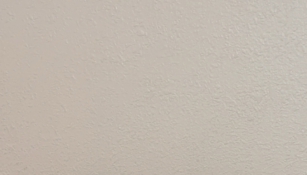 Light beige painted wall with a subtle textured plaster surface.