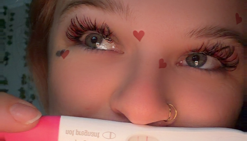 Close-up of a person with heart face filter holding a positive pregnancy test.