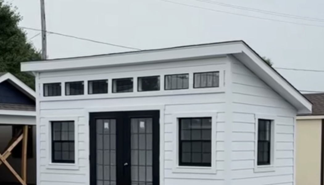 Modern white shed with black glass double doors, matching side windows, and transom windows along the top.