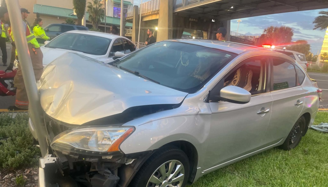 Silver sedan with a severely crumpled hood crashed head-on into a metal pole.