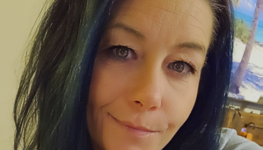 Close-up portrait of a woman with long dark hair and a gentle smile looking at the camera.