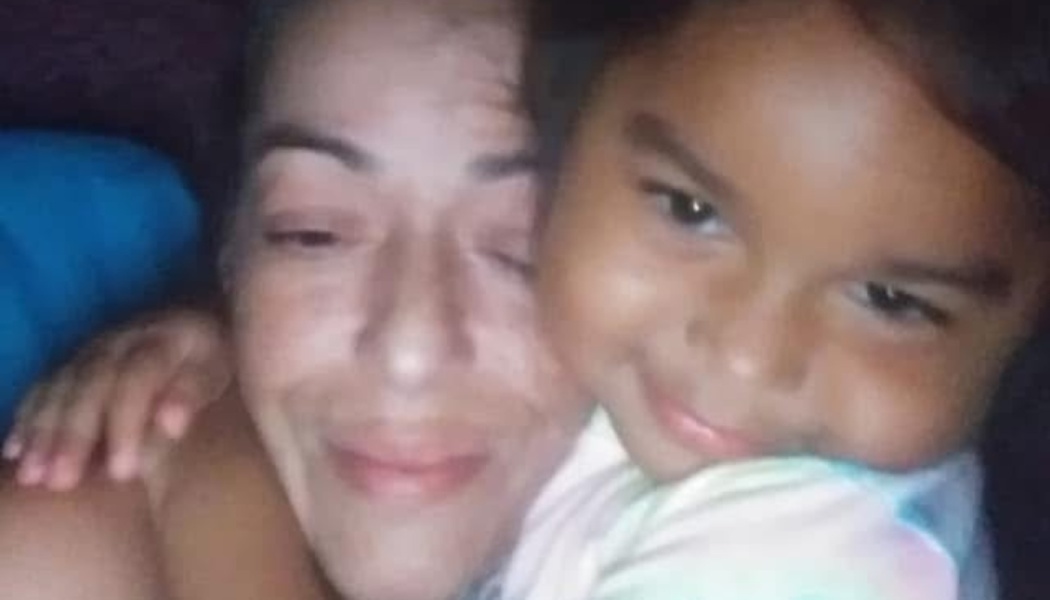A smiling woman and a young girl embracing each other closely.