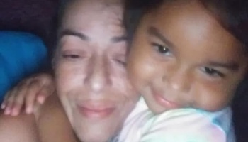 A smiling woman and a young girl embracing each other closely.
