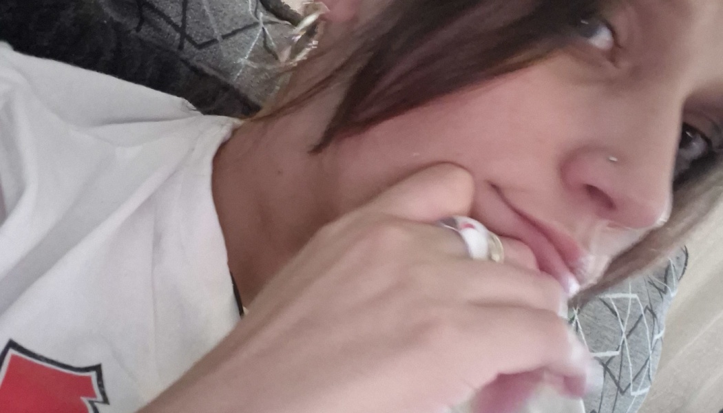 Close-up selfie of a person in a white t-shirt resting their chin thoughtfully on a hand wearing rings.