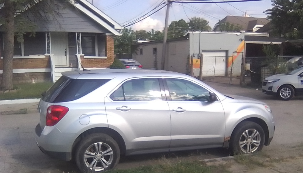 A silver Chevrolet Equinox SUV parked on a residential street in front of a house.