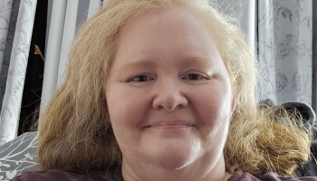 Fair-skinned woman with long, voluminous blonde hair smiling softly at the camera.