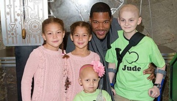 Michael Strahan smiling with four young children, including pediatric cancer patients.